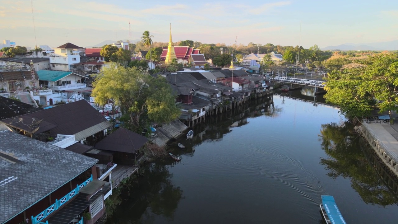 Chanthaboon滨水区(Aerial-Drone VDO) -泰国寺庙和古老的木制房屋，在日落时沿着河岸的游船旅行。视频素材