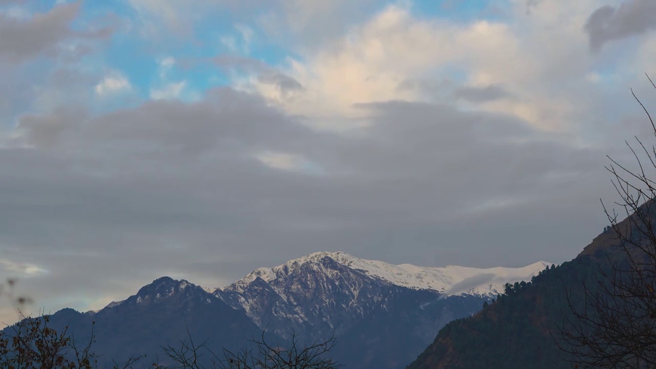 在印度喜马偕尔邦的马纳里，4K延时拍摄了早晨被积雪覆盖的山。清晨的黄光照射在被雪覆盖的喜马拉雅山脉的山顶上，把它变成了橙色。视频素材