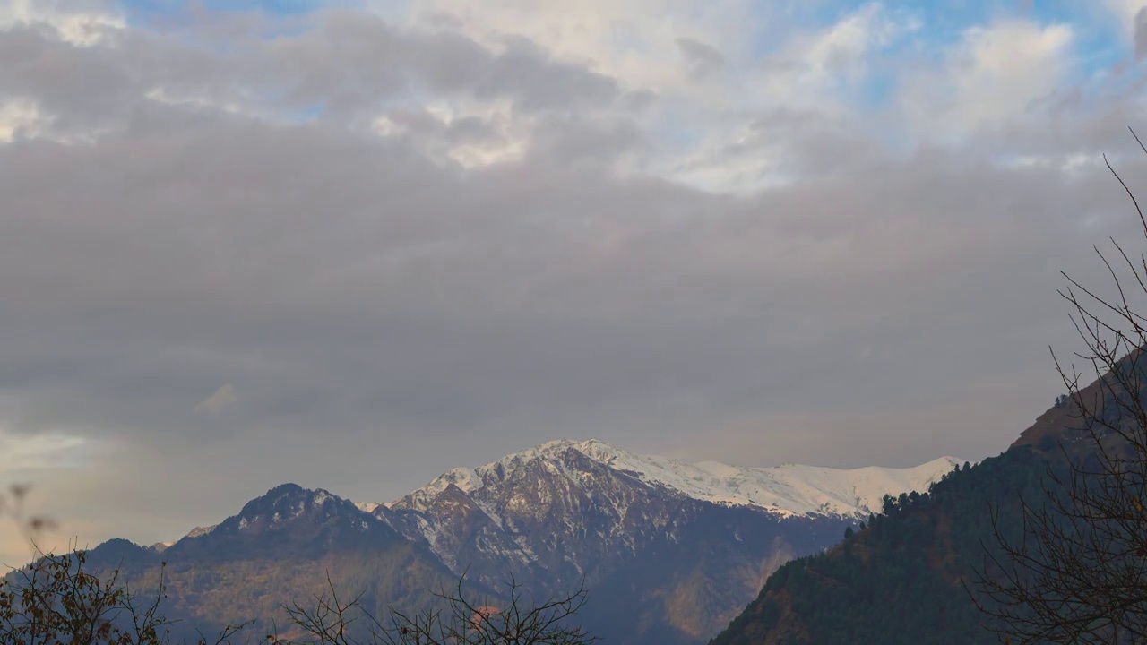 在印度喜马偕尔邦的马纳里，4K延时拍摄了早晨被积雪覆盖的山。清晨的黄光照射在被雪覆盖的喜马拉雅山脉的山顶上，把它变成了橙色。视频素材