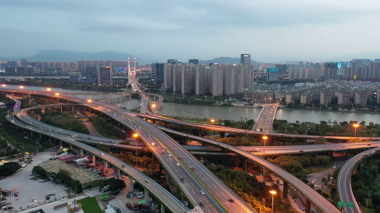 傍晚立体高架道路穿越城市河流的交通景观鸟瞰图视频素材