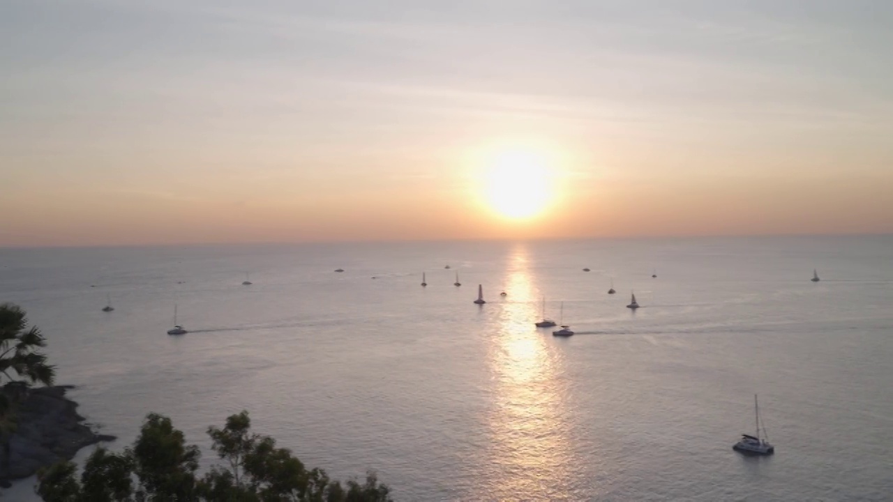 从旅游摄影角度拍摄日落黄昏时的全景海景鸟瞰图。拍摄海角黎明日落，豪华帆船在海上航行。夏季阳光热带的氛围提供复印空间。视频下载