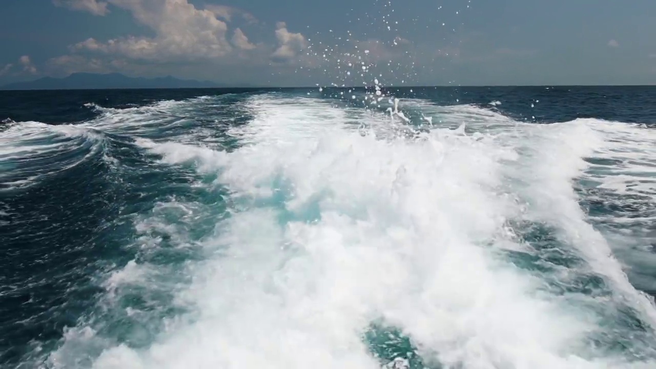 美丽的泡沫和飞溅的海水和泡沫在蓝色的大海。浮船在水面上的痕迹与羽流。慢动作视频素材