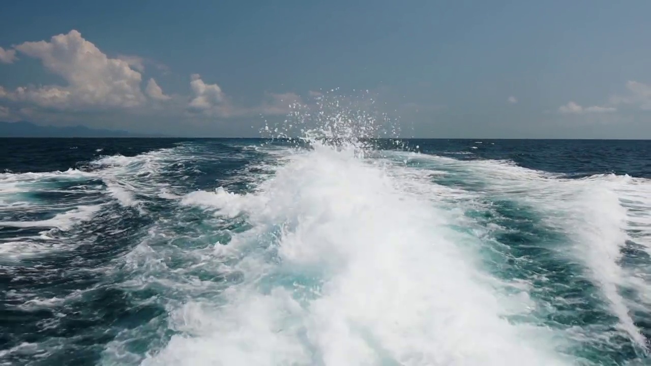 美丽的泡沫和飞溅的海水和泡沫在蓝色的大海。浮船在水面上的痕迹与羽流。慢动作视频素材