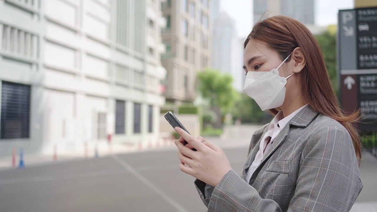 泰国曼谷，一名亚洲职业女性高管在办公大楼背景的街道上使用手机。视频素材