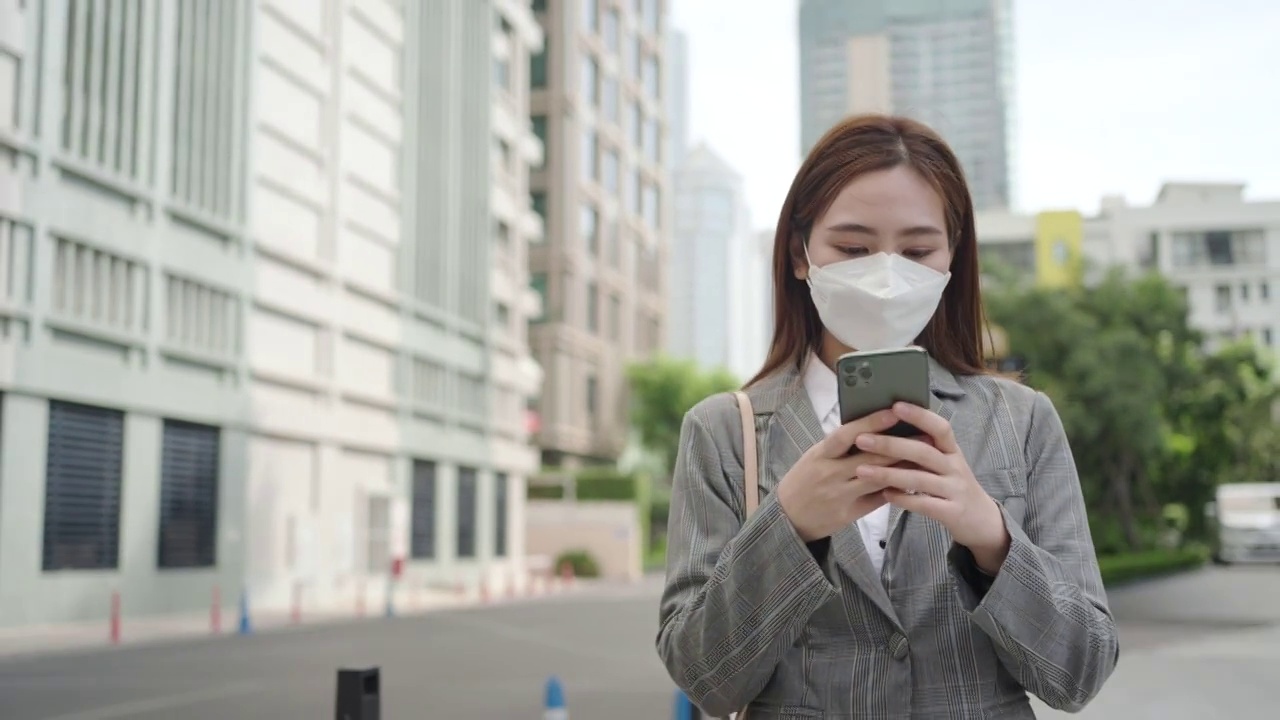 泰国曼谷，一名亚洲职业女性高管在办公大楼背景的街道上使用手机。视频素材