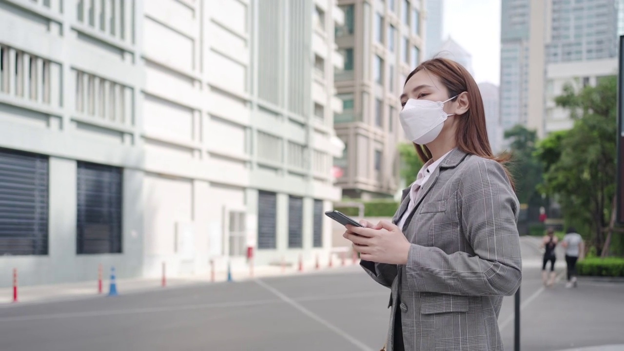 泰国曼谷，一名亚洲职业女性高管在办公大楼背景的街道上使用手机。视频素材