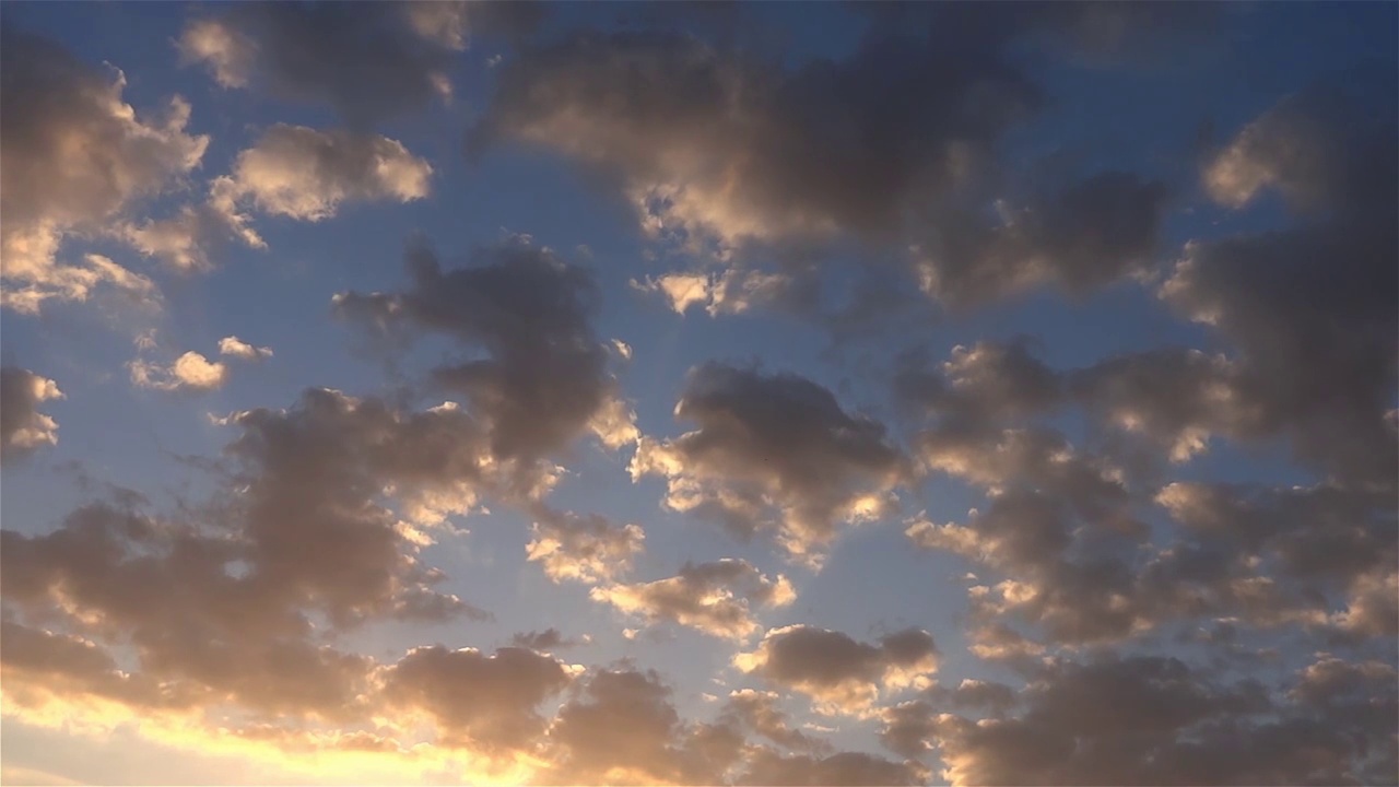 在最后一缕阳光的照耀下，蓬松的云朵穿过蓝色的天空视频素材