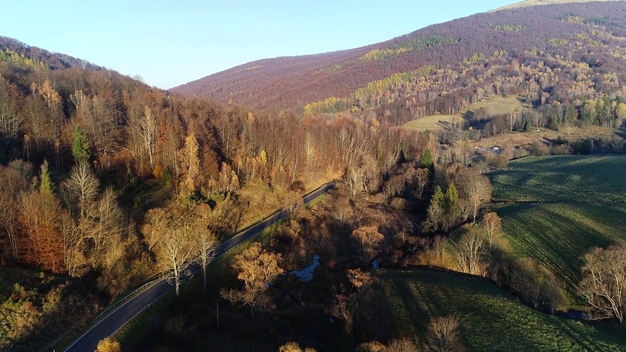 鸟瞰高山蜿蜒的道路穿过五彩缤纷的森林。9、山清水秀，秋高气爽，路过林间。史诗般的无人机镜头高速公路在野外的风景。视频素材