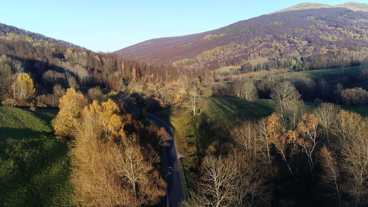 鸟瞰高山蜿蜒的道路穿过五彩缤纷的森林。9、山清水秀，秋高气爽，路过林间。史诗般的无人机镜头高速公路在野外的风景。视频素材