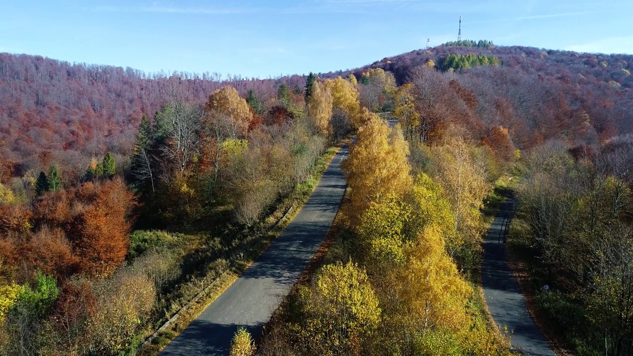 鸟瞰高山蜿蜒的道路穿过五彩缤纷的森林。9、山清水秀，秋高气爽，路过林间。史诗般的无人机镜头高速公路在野外的风景。视频素材