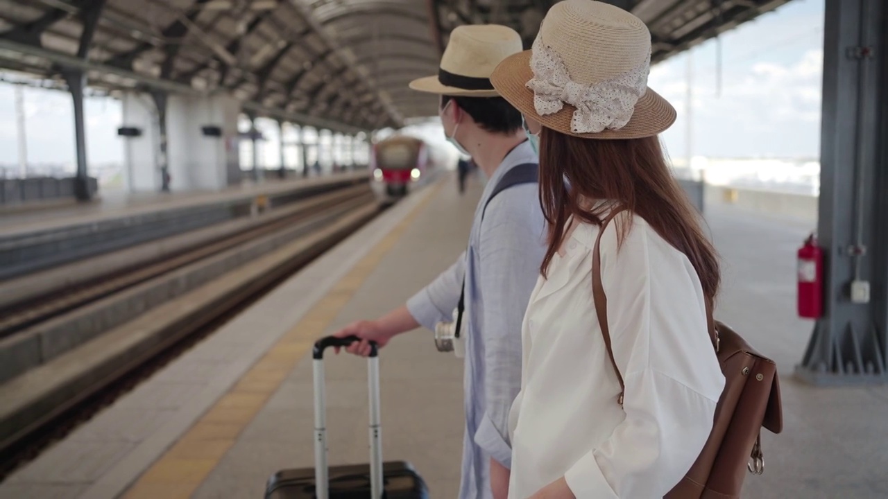 站台候车情侣——戴着医用口罩的美女和帅哥在疫情期间散步旅行——新常态生活理念视频素材