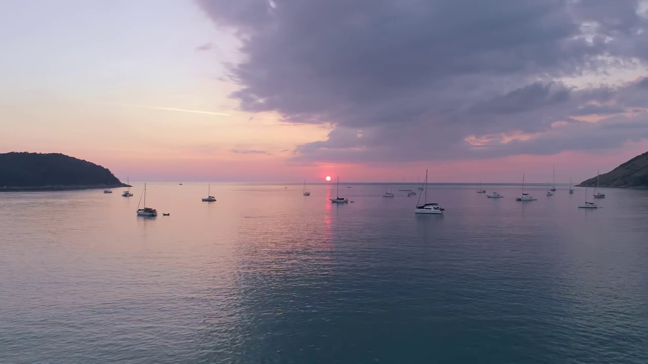 海面上五颜六色的日落与帆船航拍无人机飞越普吉岛海面反射太阳金色的光在水面上日落海洋海景夏季和旅游度假的概念视频素材