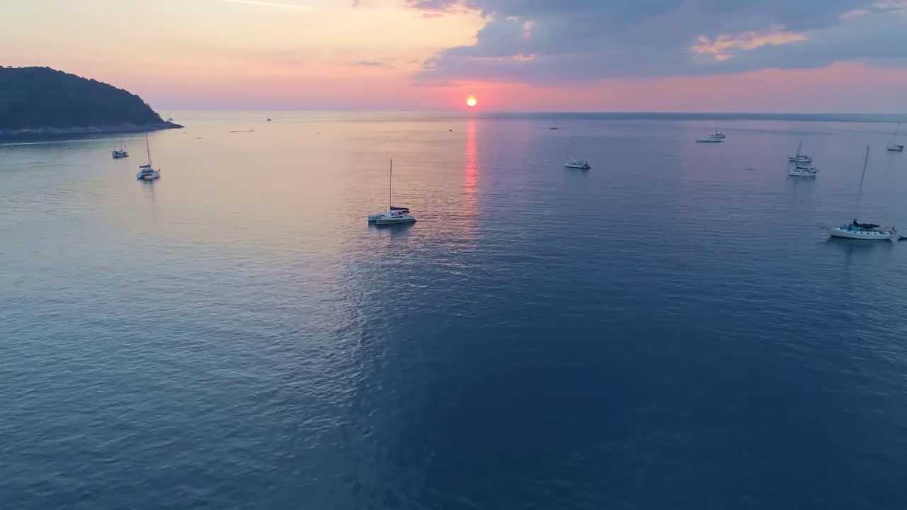 海面上五颜六色的日落与帆船航拍无人机飞越普吉岛海面反射太阳金色的光在水面上日落海洋海景夏季和旅游度假的概念视频素材