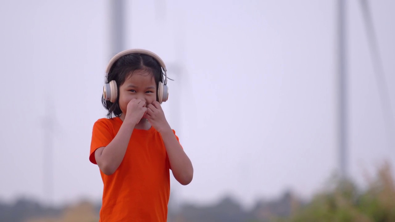 可爱的小女孩戴着耳机听音乐的肖像。视频素材