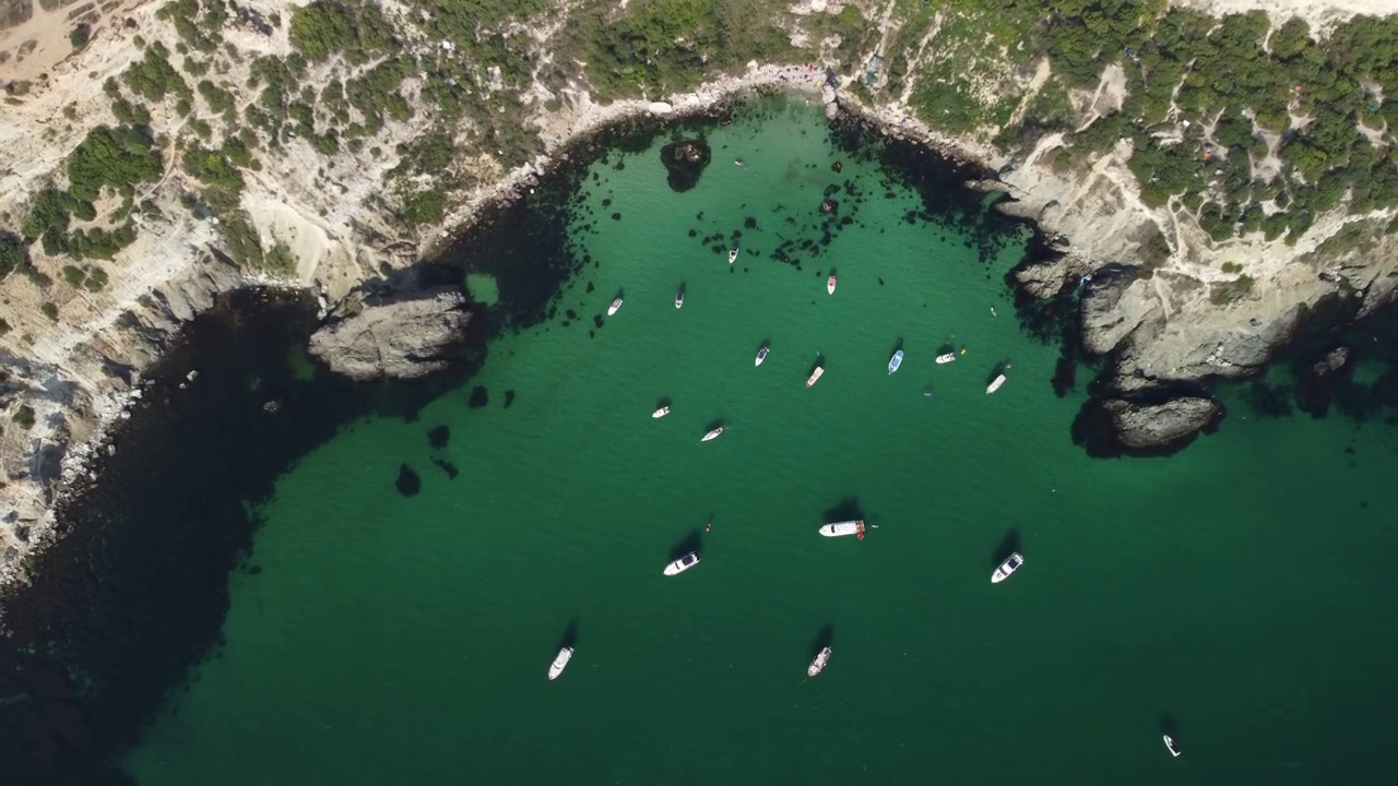 空中全景海景与湛蓝的大海和岩石海岸。在岩石的背景下，美丽的泻湖上的游艇。是夏季旅游和度假的理想目的地视频素材