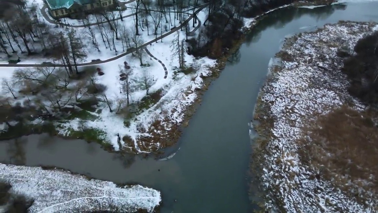 在白雪覆盖的城市公园里，在河上飞行。航空摄影。视频素材