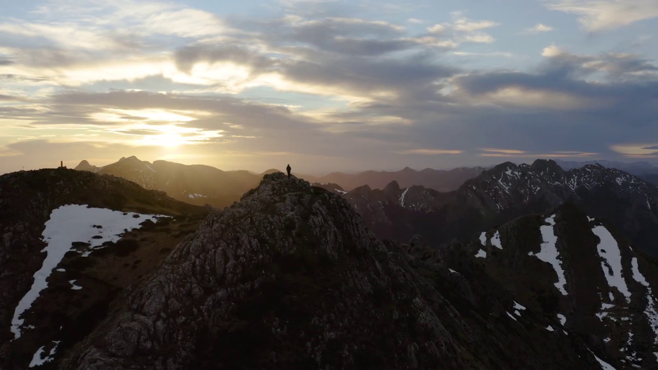 鸟瞰山景，一名徒步旅行者站在山顶。视频素材