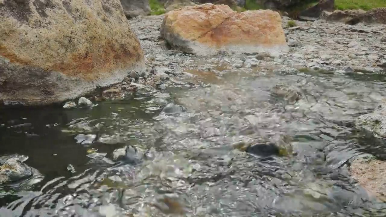 近距离拍摄4K强而急的水流，从山上流过河岸，五颜六色的石头、岩石和树木显示出强大的力量，在夏天的平静和宁静的自然度假旅行。视频素材