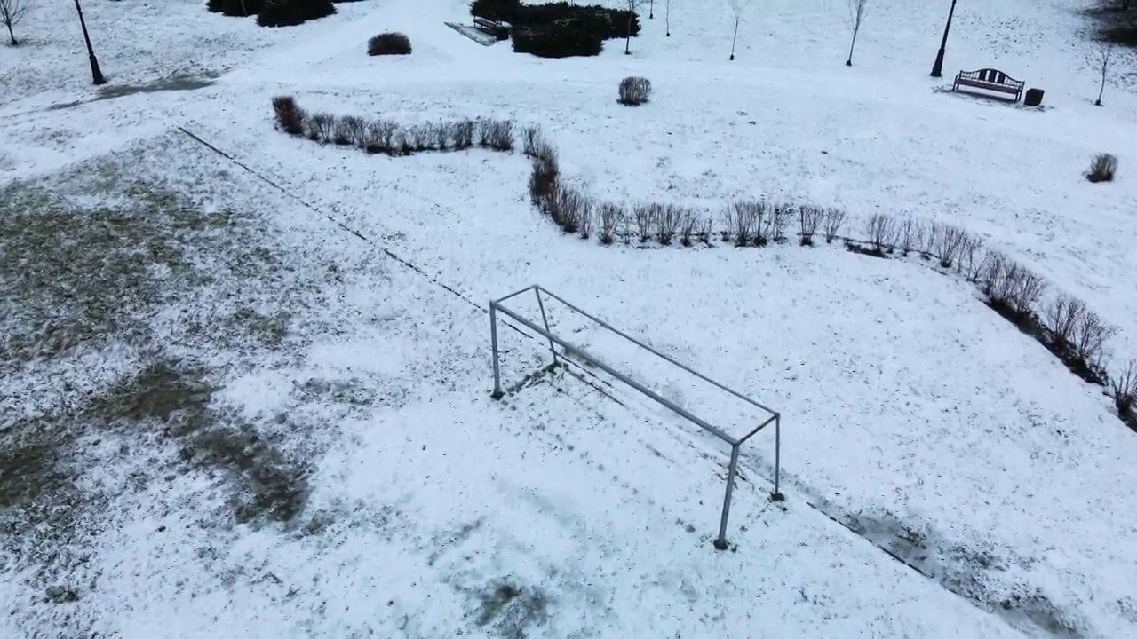 在冰雪覆盖的城市公园的运动场上空飞翔。航空摄影。视频素材