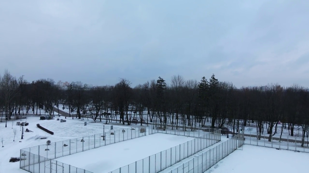 在冰雪覆盖的城市公园的运动场上空飞翔。航空摄影。视频素材