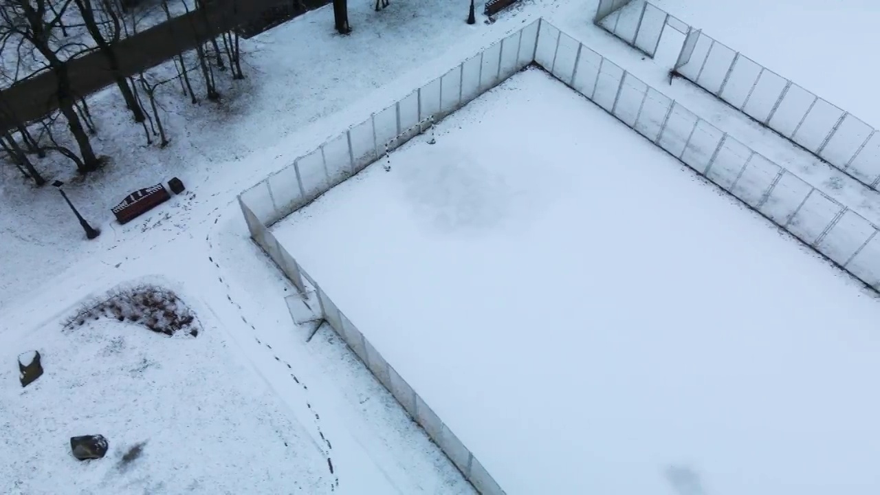 在冰雪覆盖的城市公园的运动场上空飞翔。航空摄影。视频素材