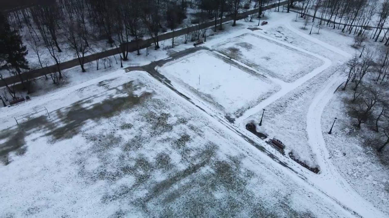 在冰雪覆盖的城市公园的运动场上空飞翔。航空摄影。视频素材