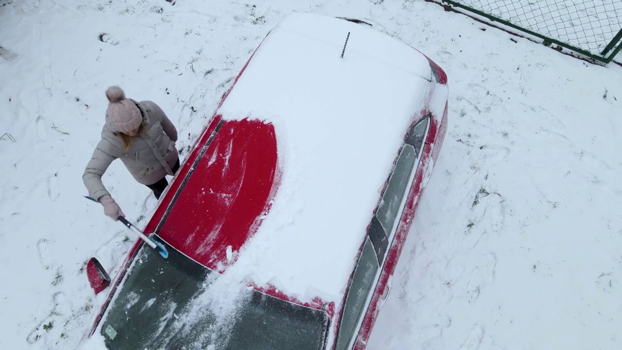 正在清理车顶积雪的妇女视频素材