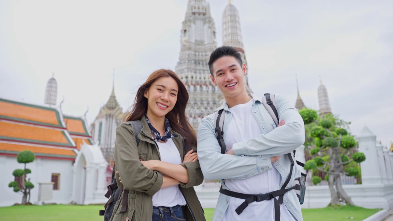 亚洲年轻夫妇在城市度蜜月旅行的写真新婚男女背包客在泰国，手挽着手，看着相机，一起享受假期。视频素材