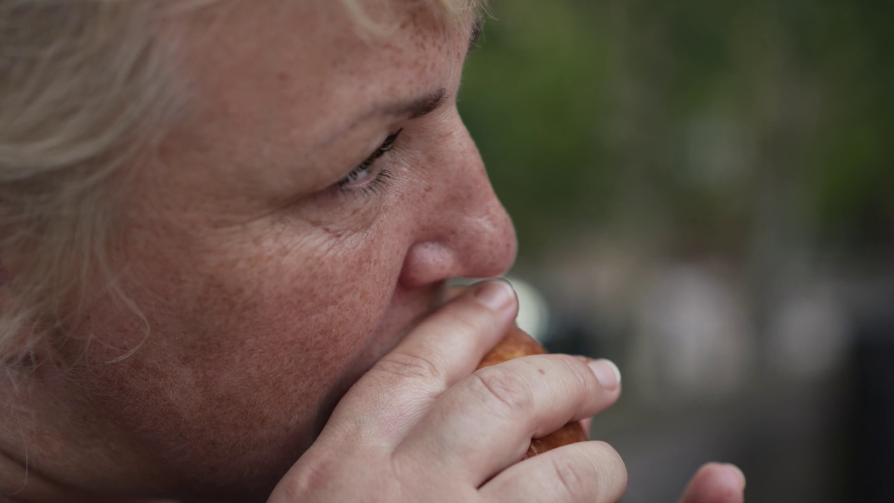 胖女人在街上吃面包。不健康食品的概念视频素材