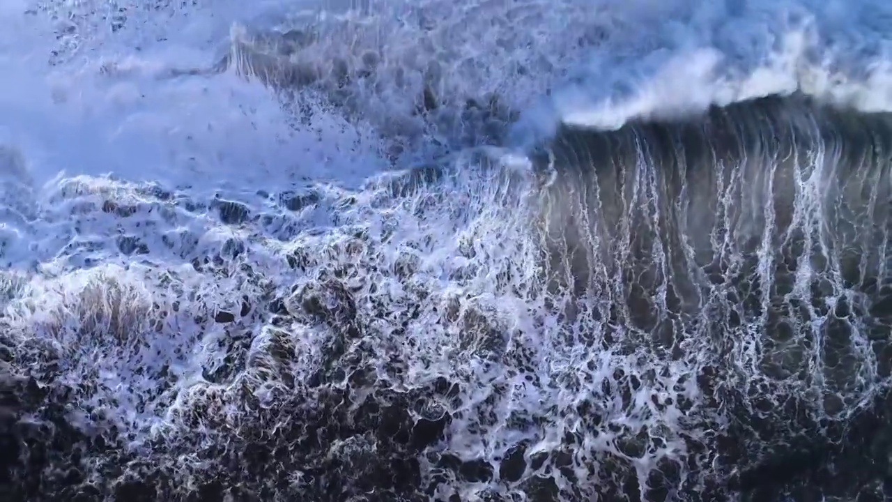 俯视图飞行的火山黑沙滩和美丽的印度洋海浪视频下载