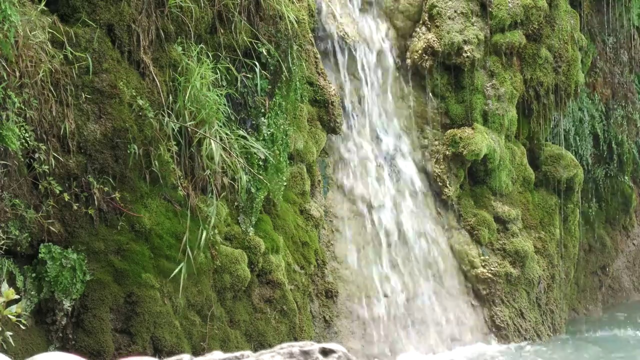 小瀑布，小溪流倾泻在长满青苔的山坡上视频素材