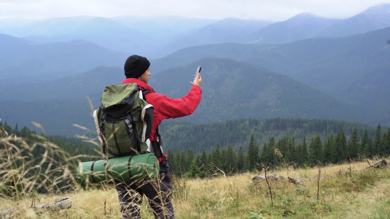 年轻的男性游客用智能手机相机拍摄山景。旅游、活跃的生活方式。视频素材