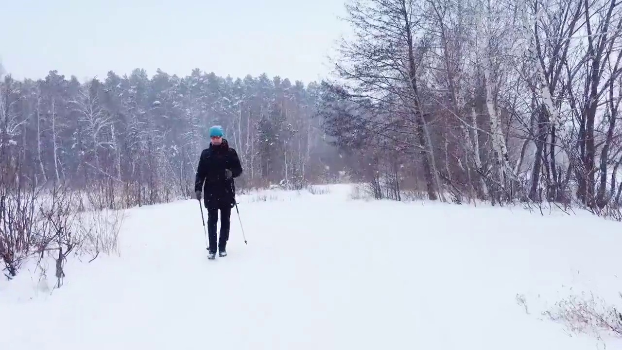 慢动作-女人在冬天的雪原森林里练习北欧漫步视频素材