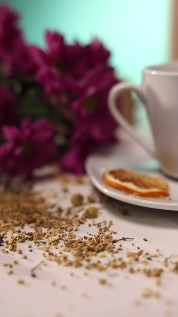 近距离观察桌子上的陶瓷茶杯，桌子上有草药，蜂蜜罐，鲜花视频素材