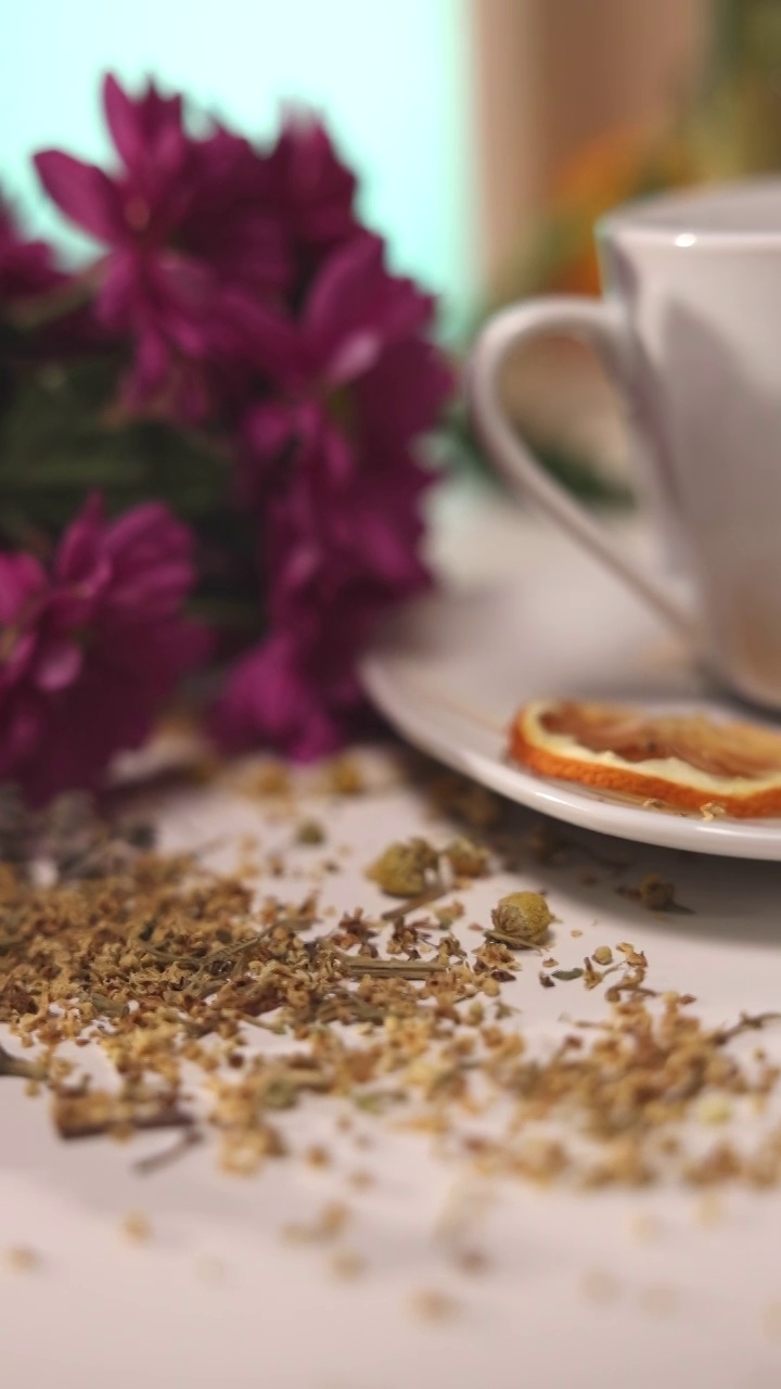 近距离观察桌子上的陶瓷茶杯，桌子上有草药，蜂蜜罐，鲜花视频素材