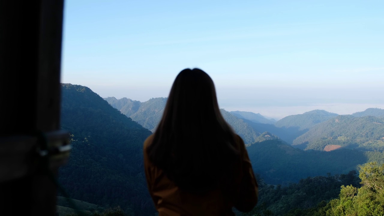 一个女人一边喝咖啡一边欣赏美丽的山景的模糊后视镜视频素材