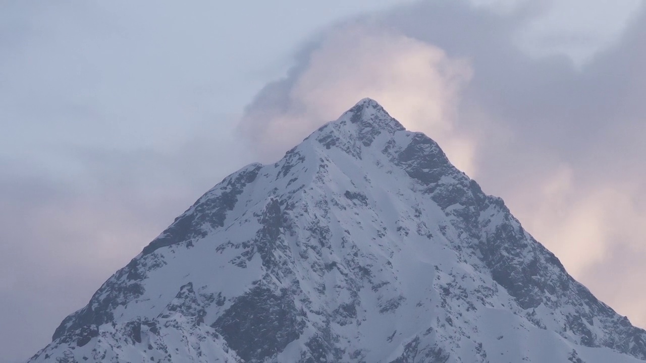 日落在雪山的山峰上，云层在山峰后面生长视频素材