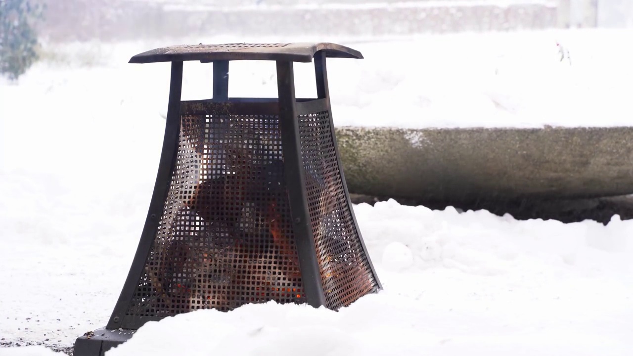 金属加热器木制营火在雪域公园在多云的冬天平静舒适的一天视频下载