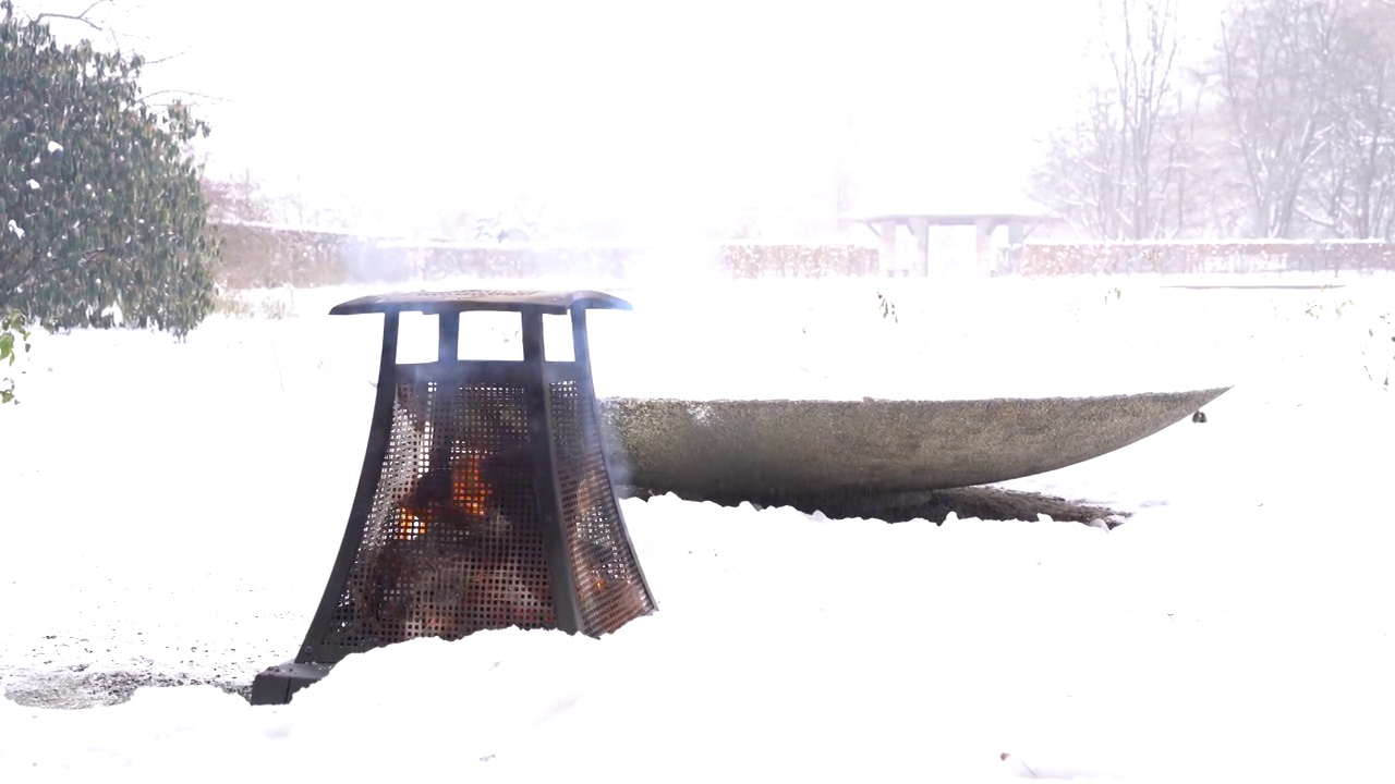 金属加热器木制营火在雪域公园在多云的冬天平静舒适的一天视频下载