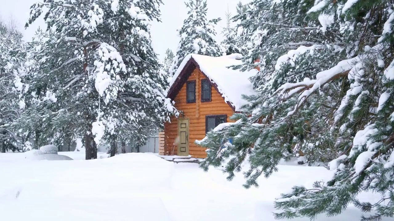 乡村的木屋，积雪的松树，大雪堆，慢慢地下雪。视频素材