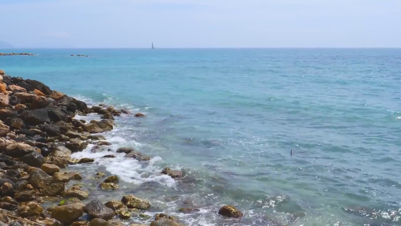 美丽的景色，蓝色的地中海与岸边的岩石海滩卵石和滚动的海浪飞溅。暑假，异国情调的旅游目的地视频素材