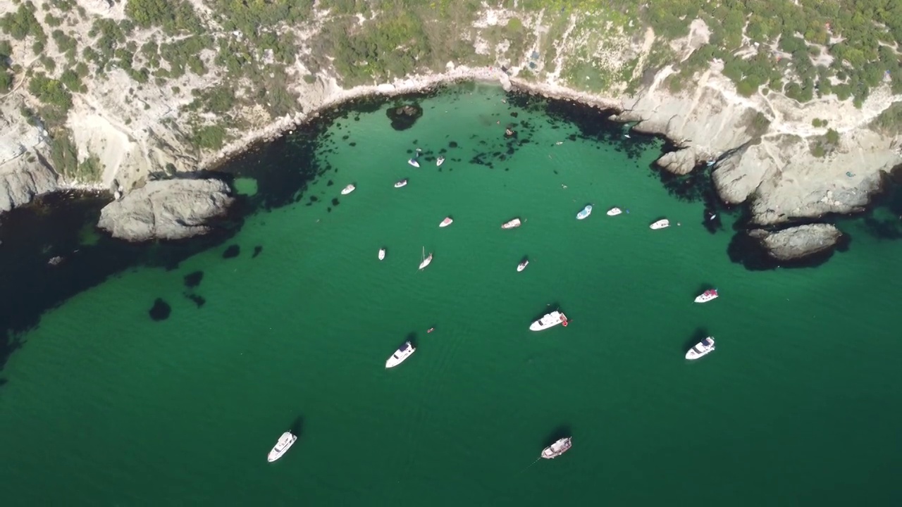 空中全景海景与湛蓝的大海和岩石海岸。在岩石的背景下，美丽的泻湖上的游艇。是夏季旅游和度假的理想目的地视频素材