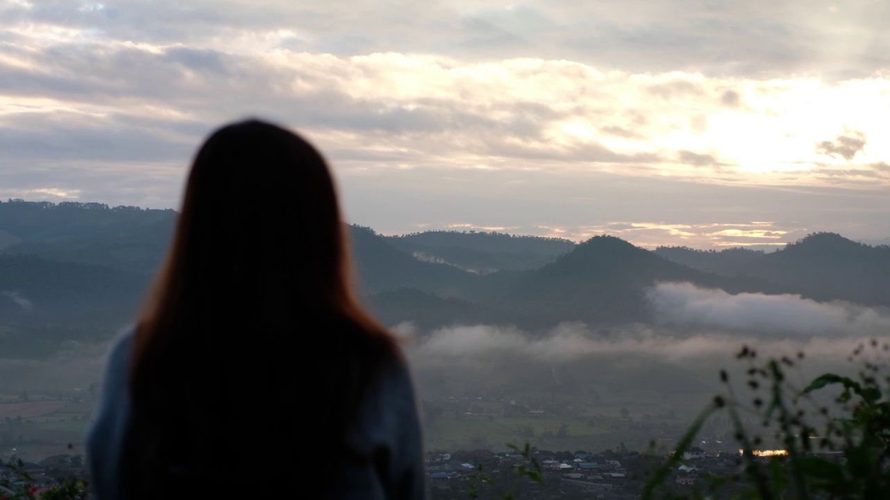 模糊的后视图的一个女性旅行者看着一个美丽的山景在雾天视频素材