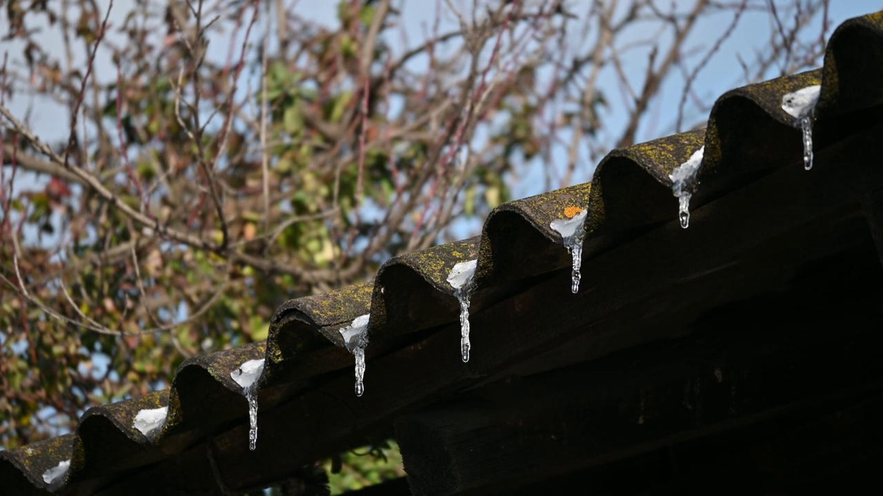 在热天，屋顶上的雪融化了。冰融化了，水从屋顶漏了出来。视频素材