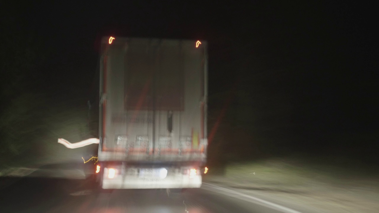 夜间在高速柏油路上行驶的货运卡车，从后面可以看到被一辆小车追赶视频素材