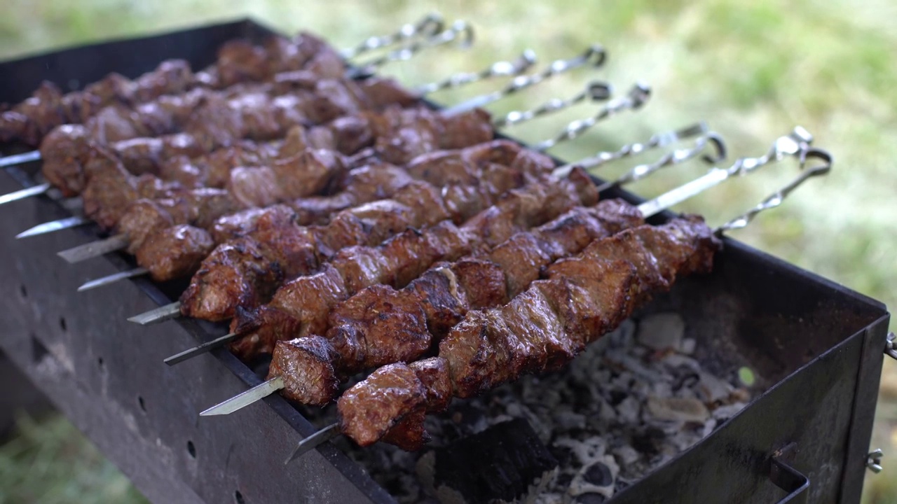 一个男人的手转动着烤肉串。羊肉串。在木炭烤架上炸的猪肉或羊肉块。剩下的时间煎烤肉块视频素材