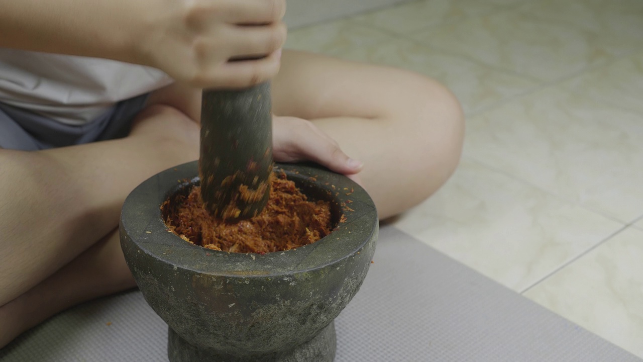 妇女们在臼中捣碎香料和药草来烹饪食物视频素材