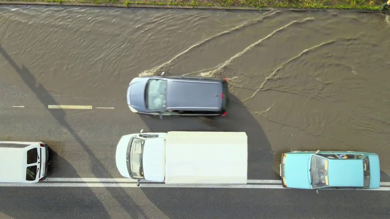 城市交通鸟瞰图，汽车行驶在暴雨后被淹没的街道上。道路排水系统的问题视频素材