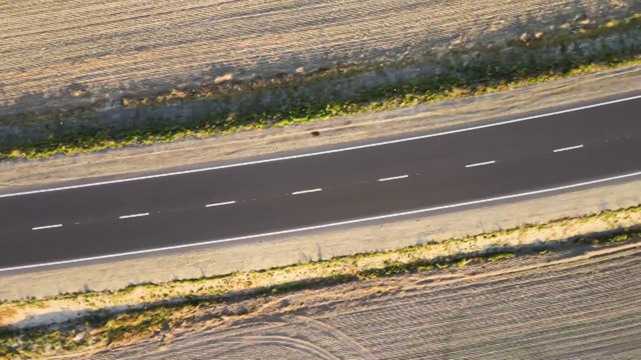 鸟瞰图的城际道路与快速行驶的汽车在日落。俯视图从无人机公路交通在晚上视频素材