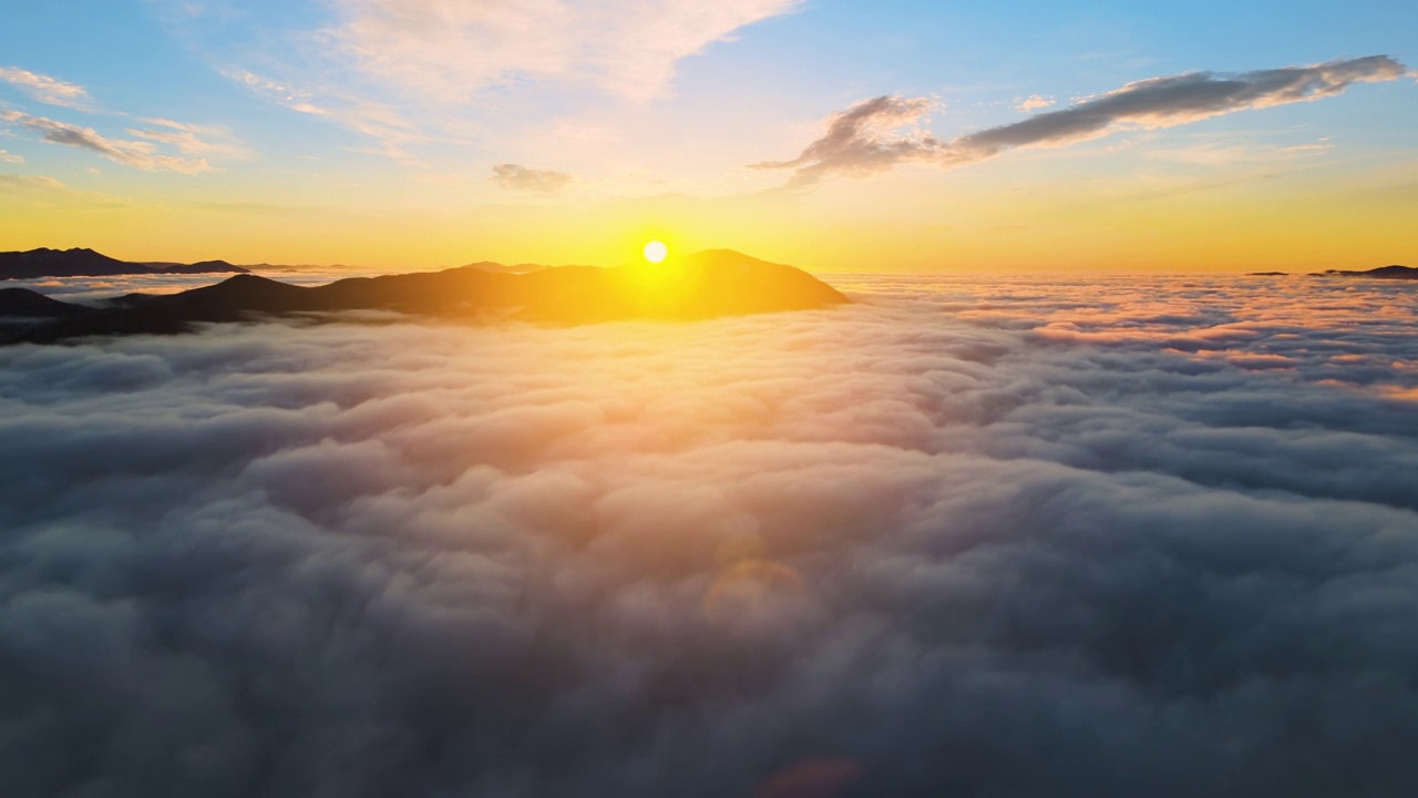 从空中俯瞰，充满活力的日出在白色浓密的云层上，远处的深色山脉在地平线上视频素材